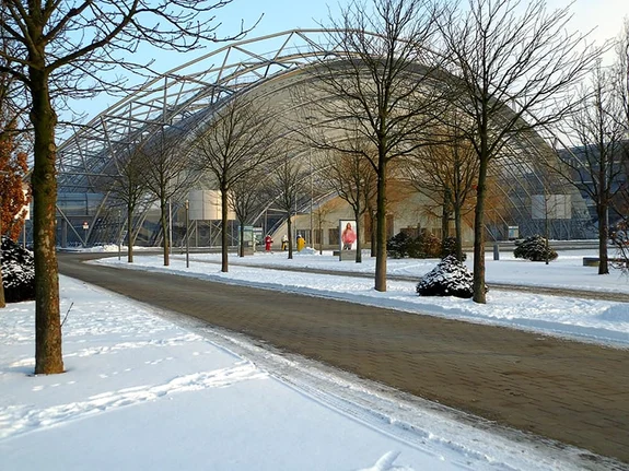 Große, bogenförmige Glaskonstruktion einer Messehalle im Winter.