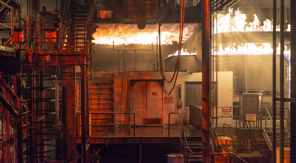 Flammen lodern kontrolliert in einer industriellen Test- oder Übungsanlage.