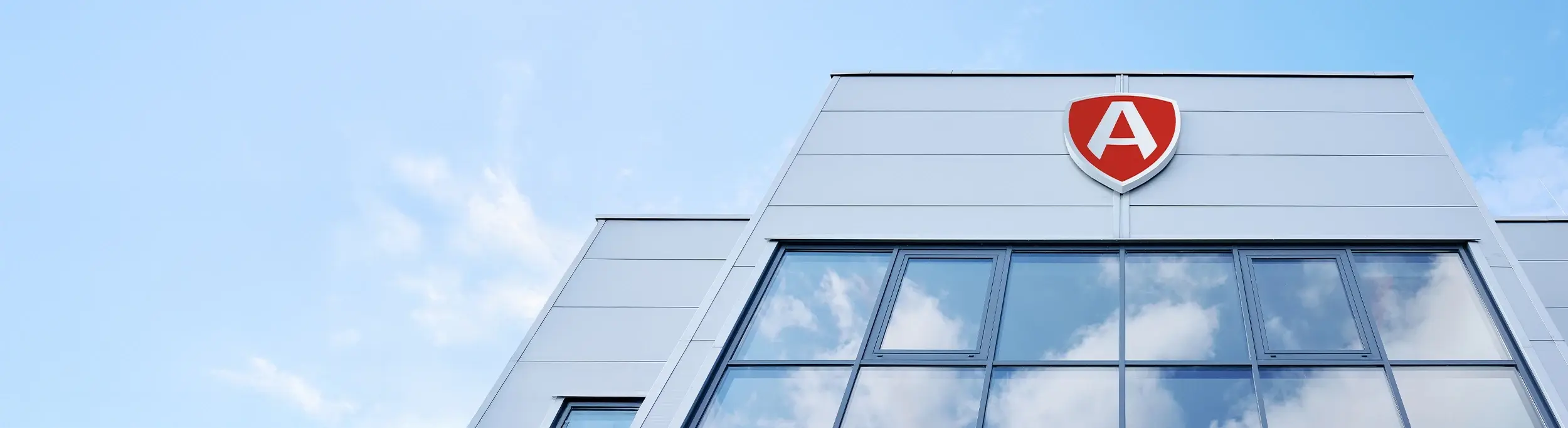 Modernes Bürogebäude mit markantem rotem ARTUS Wappenschild vor blauem Himmel.